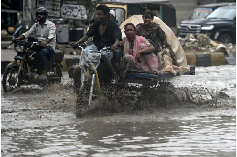 Commuters make their way through a flooded street after heavy rainfall in Karachi. Commuters make their way through a flooded street after heavy rainfall in Karachi